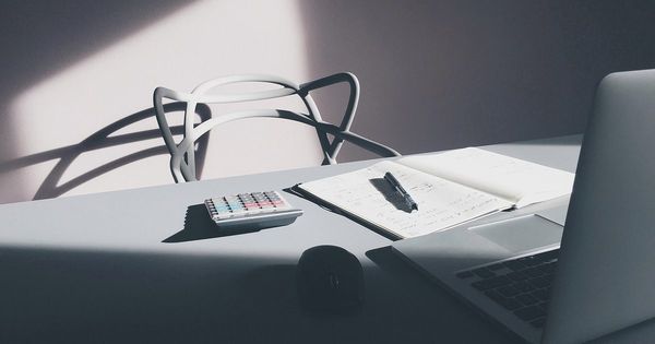 Escritorio con una calculadora, un cuaderno con anotaciones y un computador portátil
