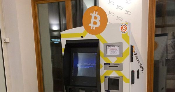 Cajero de bitcoin con pantalla y lectores de tarjeta, junto a una ventana con marco de madera
