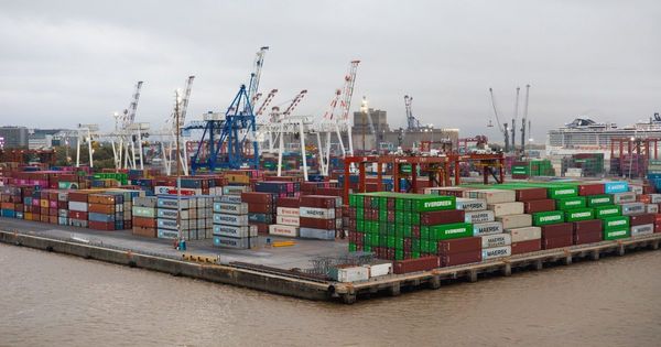 Terminal portuaria con contenedores apilados y grúas junto al agua